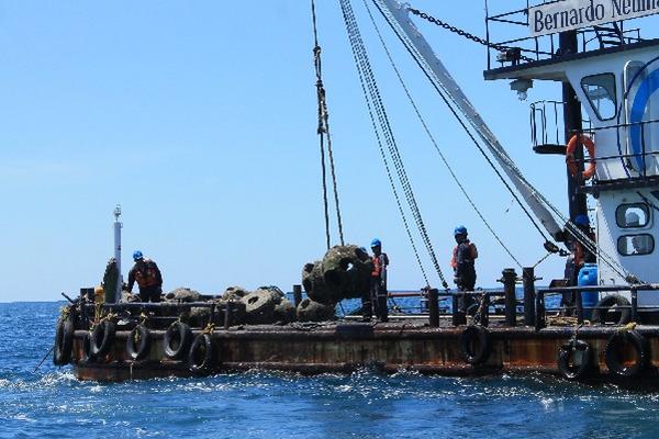 Personal  de la Empresa Portuaria Quetzal traslada estructuras en barcaza.