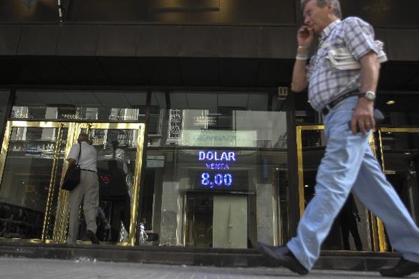 Un peatón, en Buenos Aires, pasa frente a una casa de cambio, en la cual se vende a ocho pesos argentinos el dólar. (Foto Prensa Libre: EFE)