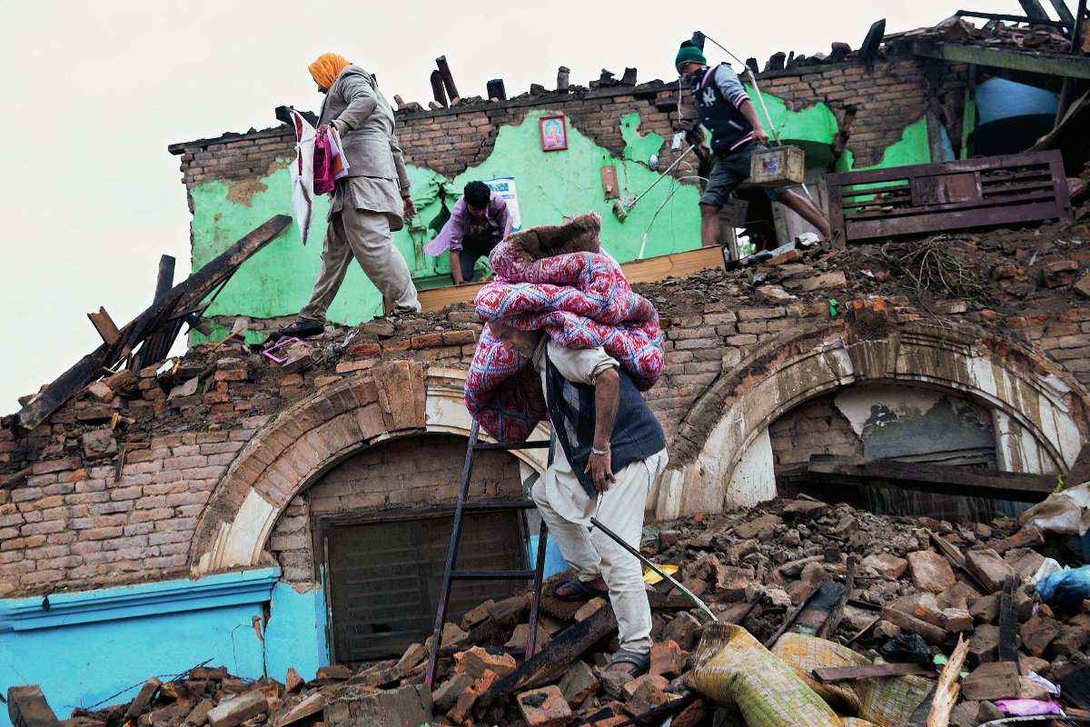 Sobrevivientes del terremoto rescatan pertenencias de una casa que fue dañada en Katmandú, Nepal, (Foto Prensa Libre AP)