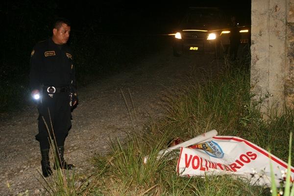 Agente de la PNC observa el cadáver de un hombre que fue baleado en la ruta entre Cobán y Chisec. (Foto Prensa Libre: Ángel Tax)<br _mce_bogus="1"/>