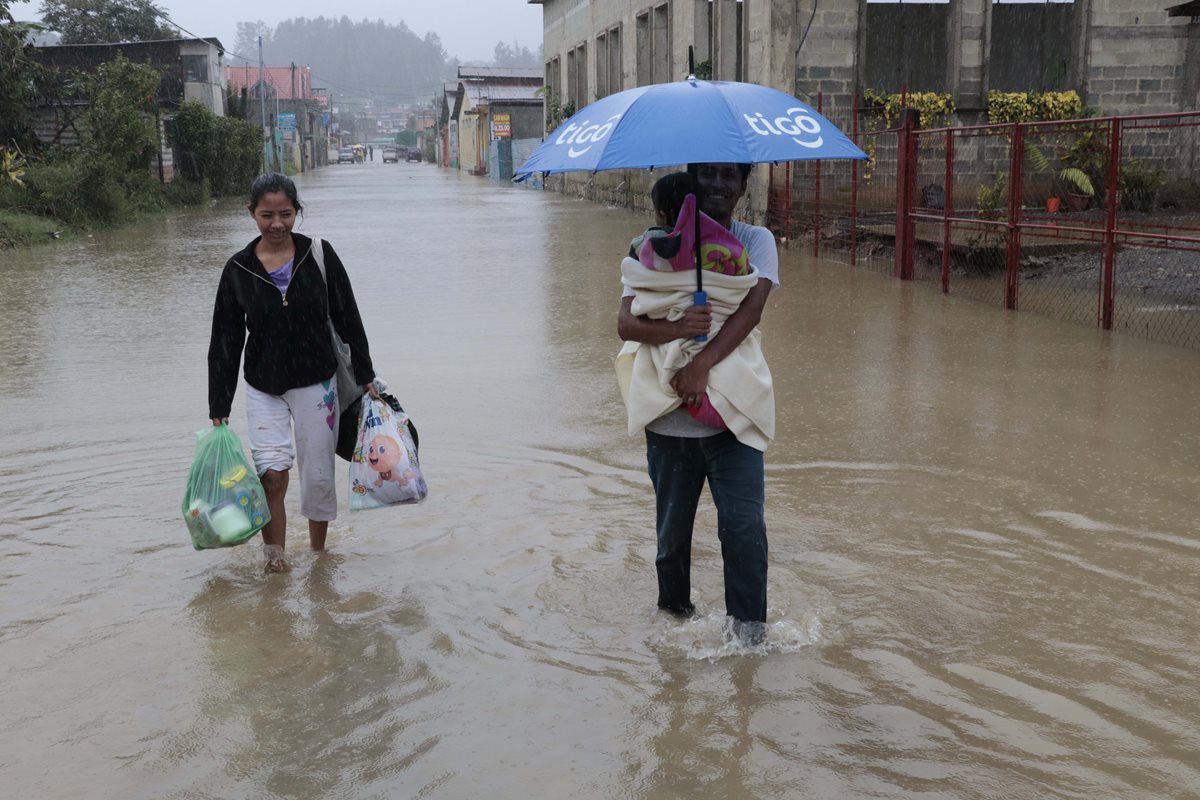 Carlos García junto a su familia caminan por una de las calles de Residenciales Imperial, zona 7, de Cobán, que fue inundada por la crecida del río Cahabón. (Foto Prensa Libre: Eduardo Sam Chun)