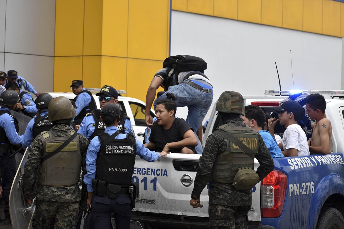 Miembros de la policía detienen a un grupo de ciudadanos durante saqueos en San Pedro Sula
