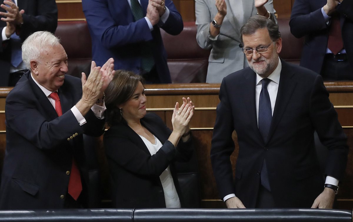Legisladores del PP aplauden a Mariano Rajoy que se pone de pie, al ser reelecto para presidir el gobierno español. (Foto Prensa Libre: EFE).