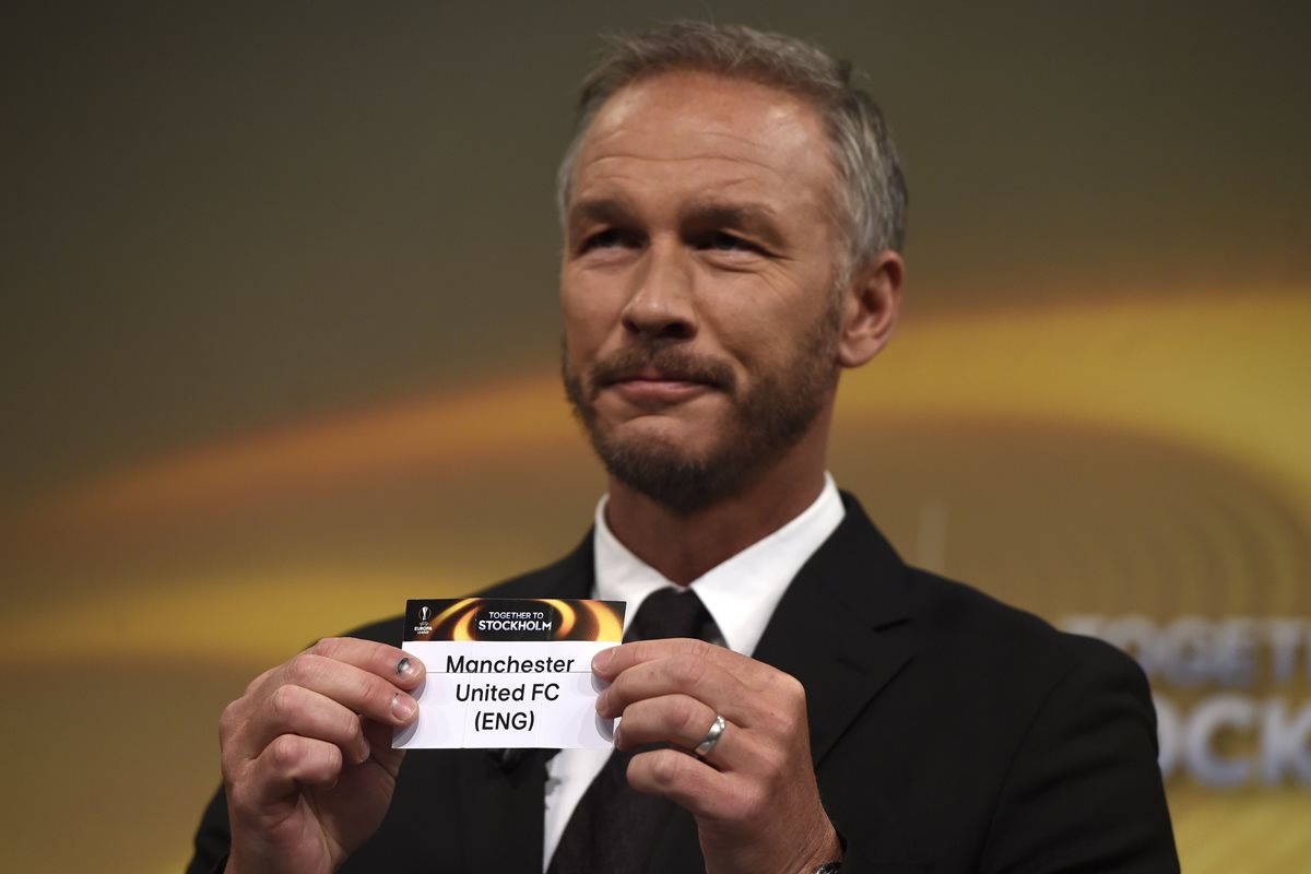 Patrik Andersson, embajador de la UEFA, muestra el nombre del Manchester United en el sorteo de los octavos de final. (Foto Prensa Libre: AFP)