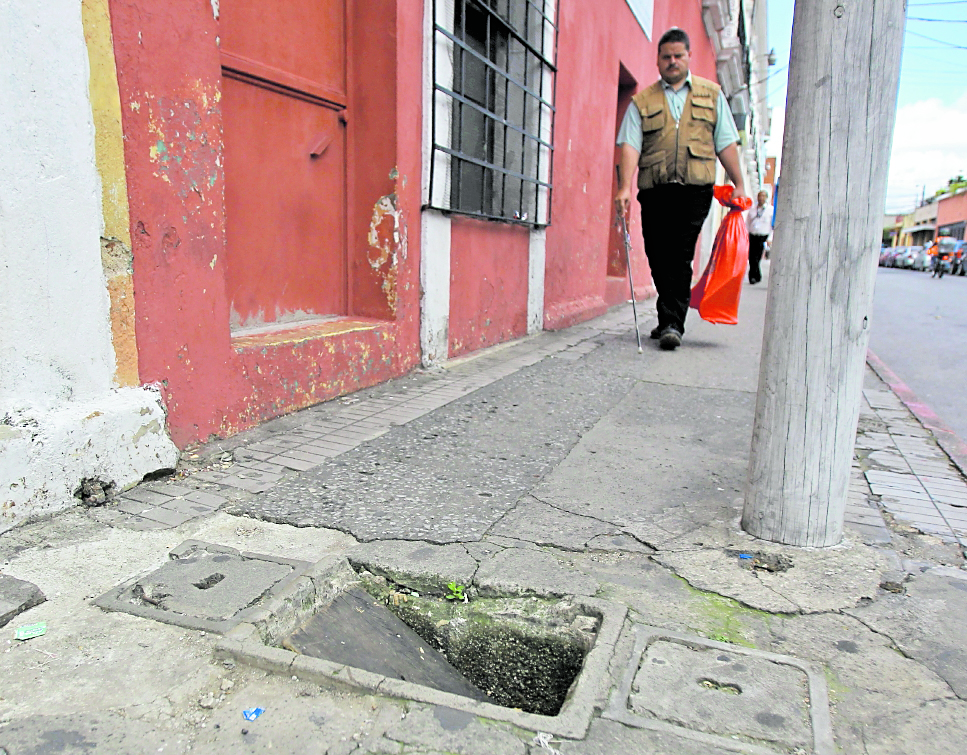 Edwin Sulín, quien tiene dificultad visual, camina por banqueta en mal estado en la 10 calle, entre 11 y 12 avenidas de la zona 1. (Foto Prensa Libre: Esbin García)