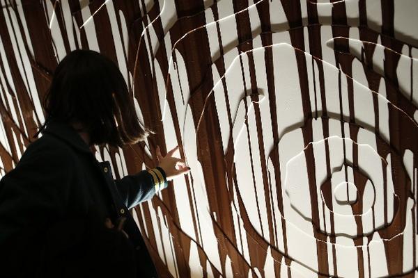 Una mujer unta su dedo con chocolate que se escurría por una pared durante la apertura de la Semana de la Moda de Nueva York, el domingo pasado. (Foto Prensa Libre: AP)