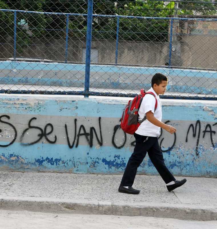 Un estudiante pasa frente a un graffiti hecho por la pandilla Mara Salvatrucha en el barrio El Bosque.(Foto Prensa Libre:AFP).
