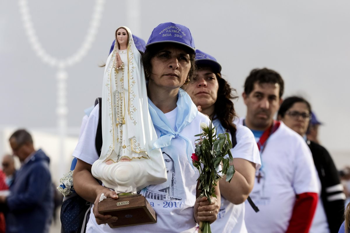 Una mujer sostiene una imagen de la Virgen de Fátima cerca al Santuario de Fátima. (Foto Prensa Libre: EFE)