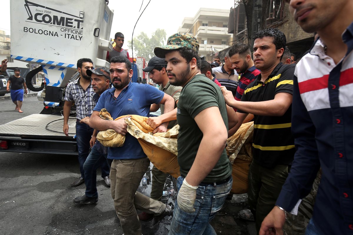 Un grupo de hombres saca de los escombros los restos de una víctima del mortífero atentado en Bagdad. (Foto Prensa Libre: AFP).