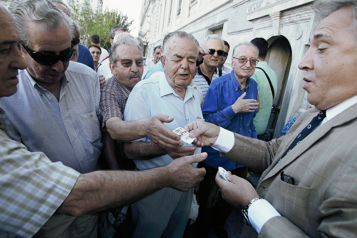 Un empleado reparte turnos  frente a una sucursal del Banco Nacional de Grecia en  Atenas. (Foto Prensa Libre:EFE)