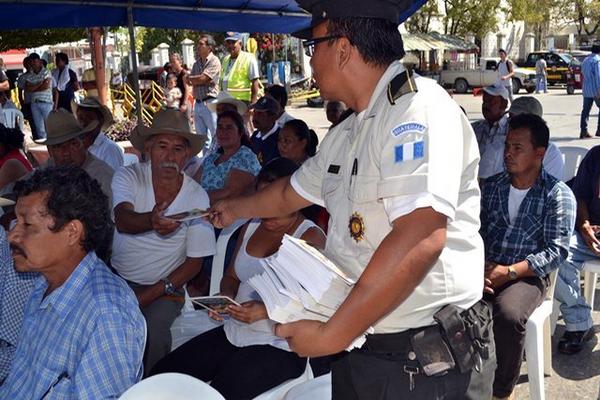 Un agente entrega un folleto con información del plan de seguridad a un vecino de Sanarate. (Foto Prensa Libre: Hugo Oliva) <br _mce_bogus="1"/>