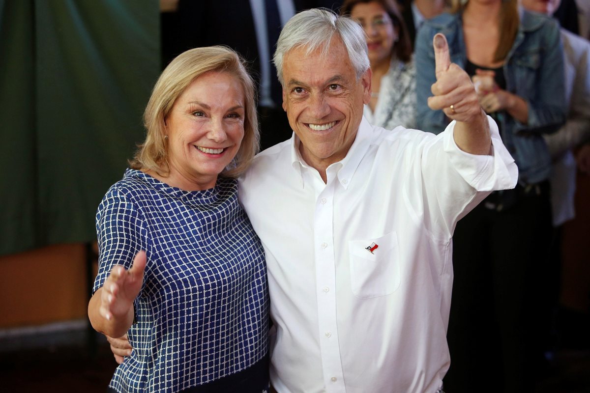 Sebastián Piñera (junto a su esposa Cecilia Morel) saluda a los chilenos, luego de emitir su voto. (Foto Prensa Libre: EFE)