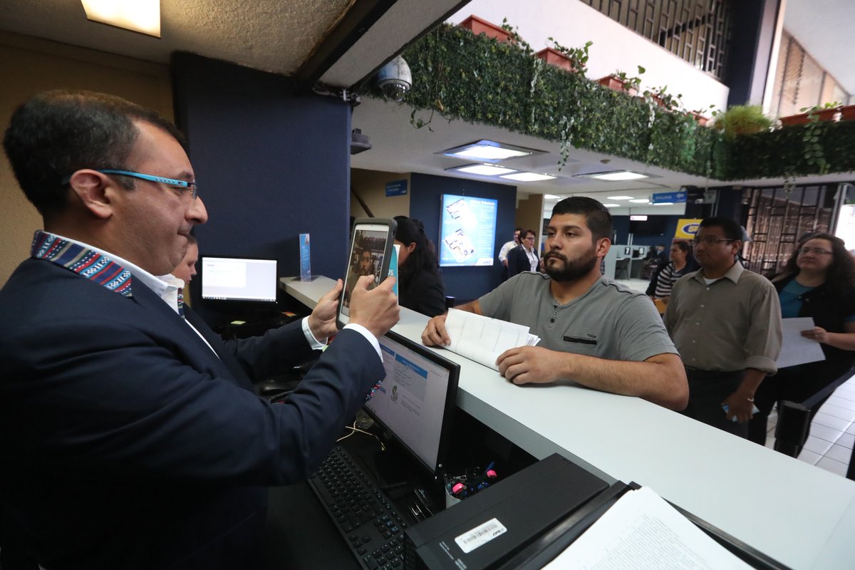 Un empleado de la SAT identifica a una persona y registra en el nuevo sistema de filas su trámite. (Foto Prensa Libre: Mynor Toc)