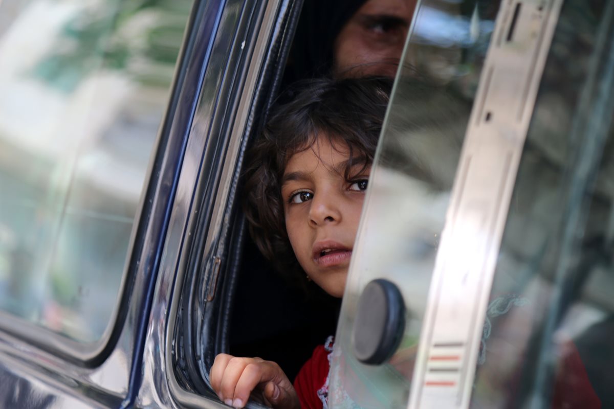 Un niño sirio observa desde la ventana de un vehículo. (Foto Prensa Libre: AFP).