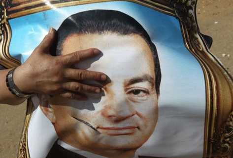 Un seguidor de Hosni Mubarak sostiene un retrato suyo. (Foto Prensa Libre: AFP)