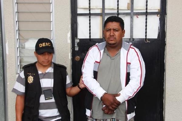 Un agente conduce a Henry Oliveros  Muralles, detenido por la Policía en Villa Nueva. (Foto Prensa Libre: PNC)
