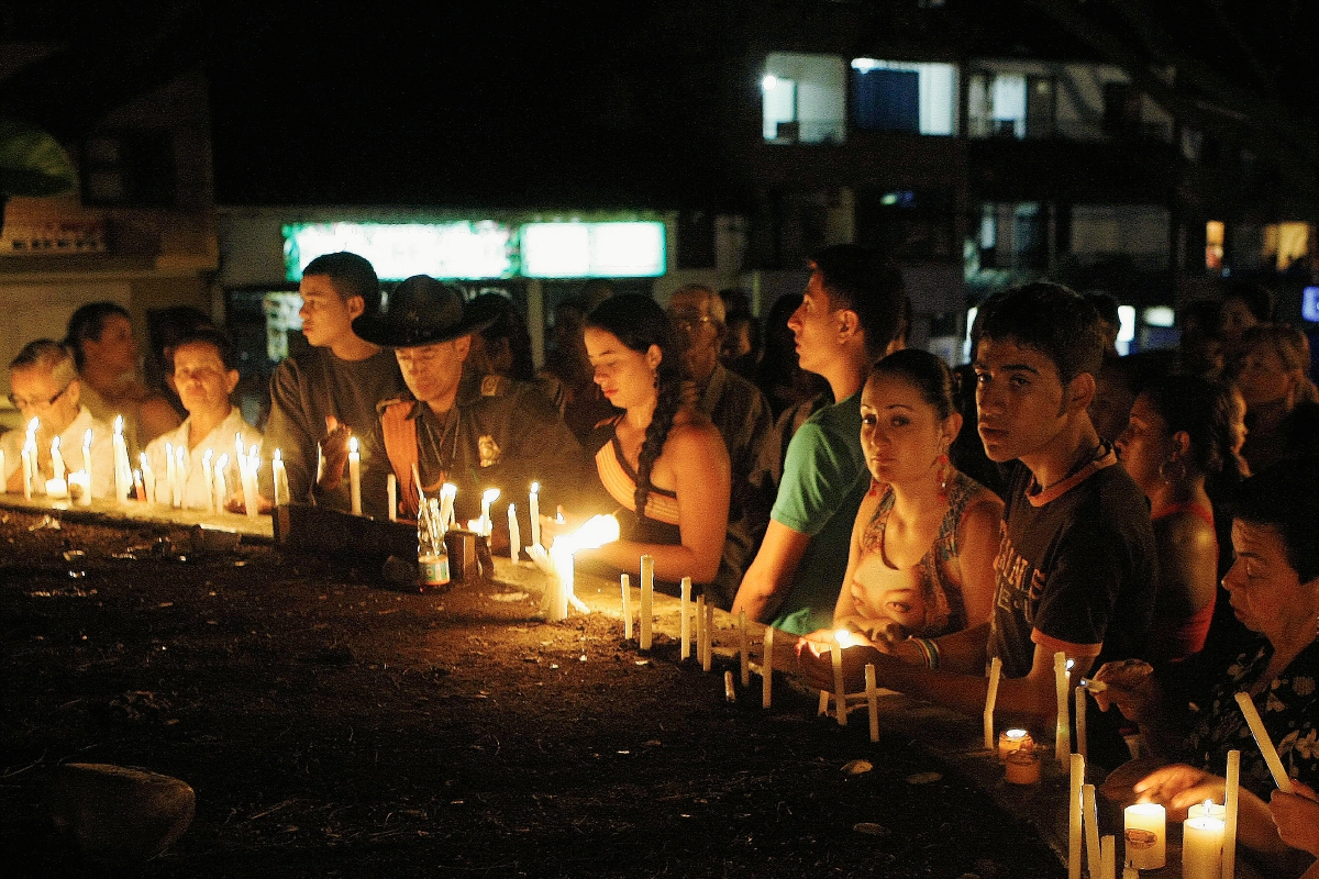 Pobaldores encienden velas durante una vigilia por las víctimas de la avalancha. (Foto Prensa Libre:EFE)