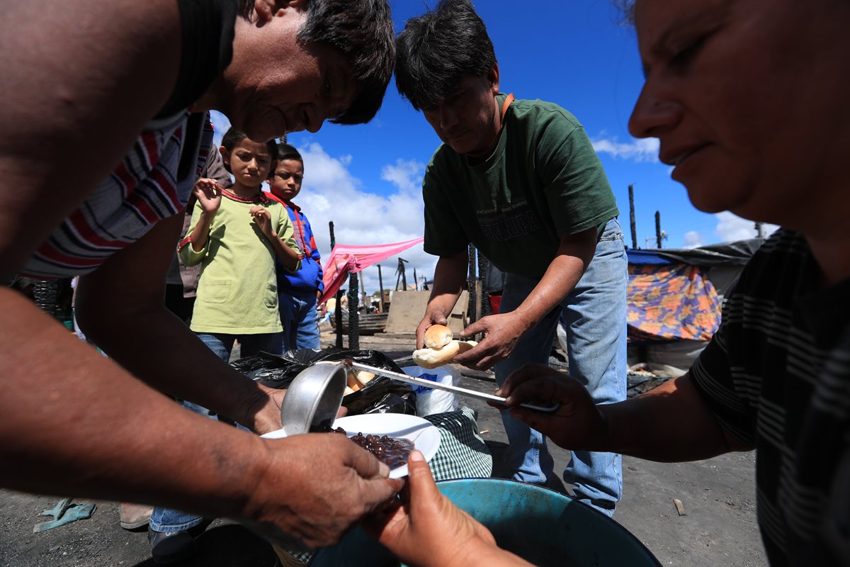 Niños y adultos hacen fila para recibir alimentos en el asentamiento Los Pinos, zona 3. Los afectados no tienen alimentos. (Foto Prensa Libre: Carlos Hernández)