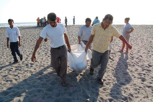Uno de los cadáveres es retirado de la playa.