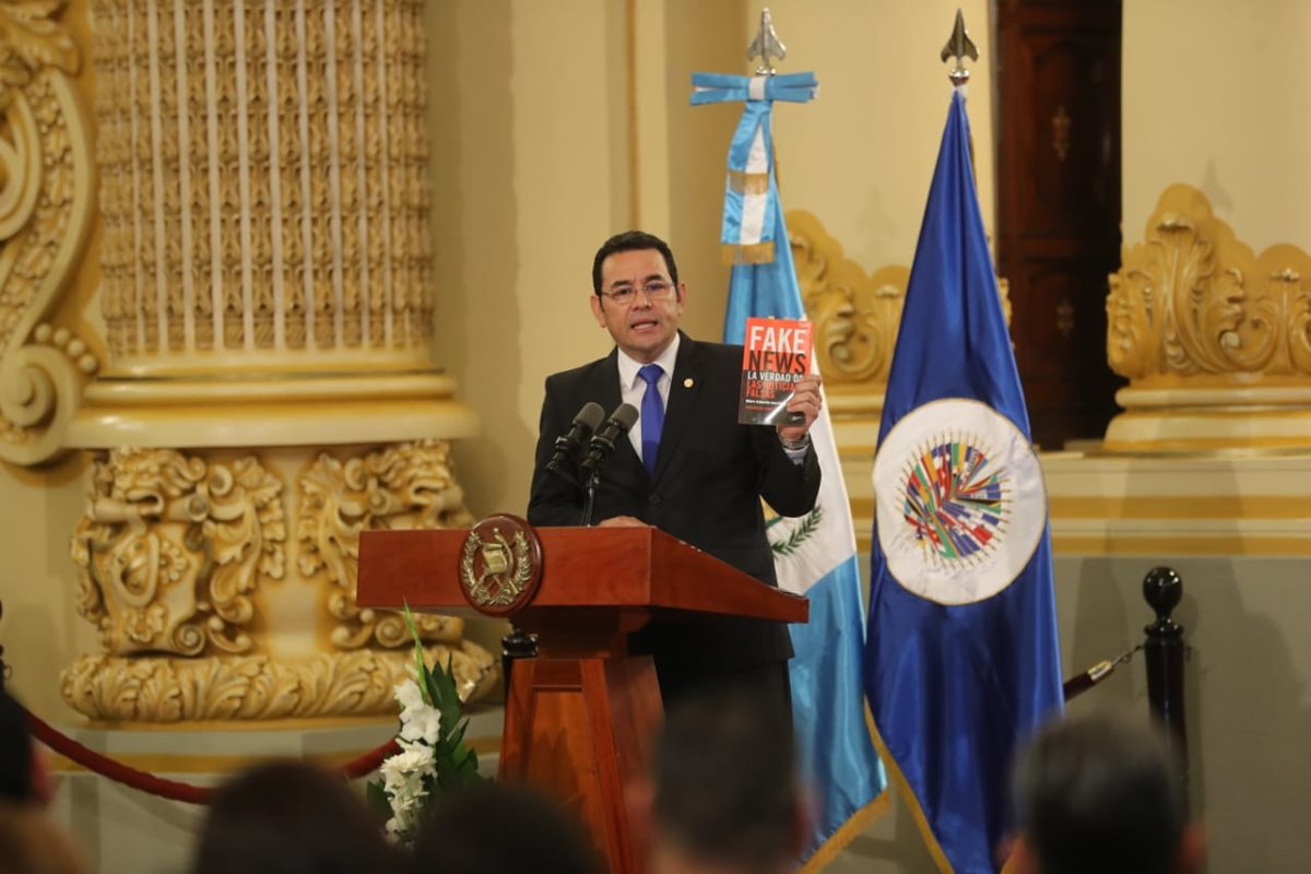 El presidente Jimmy Morales sostiene una copia del libro “Fake news: La verdad de las noticias falsas” escrito por Marc Amorós García. (Foto Prensa Libre: Erick Ávila)