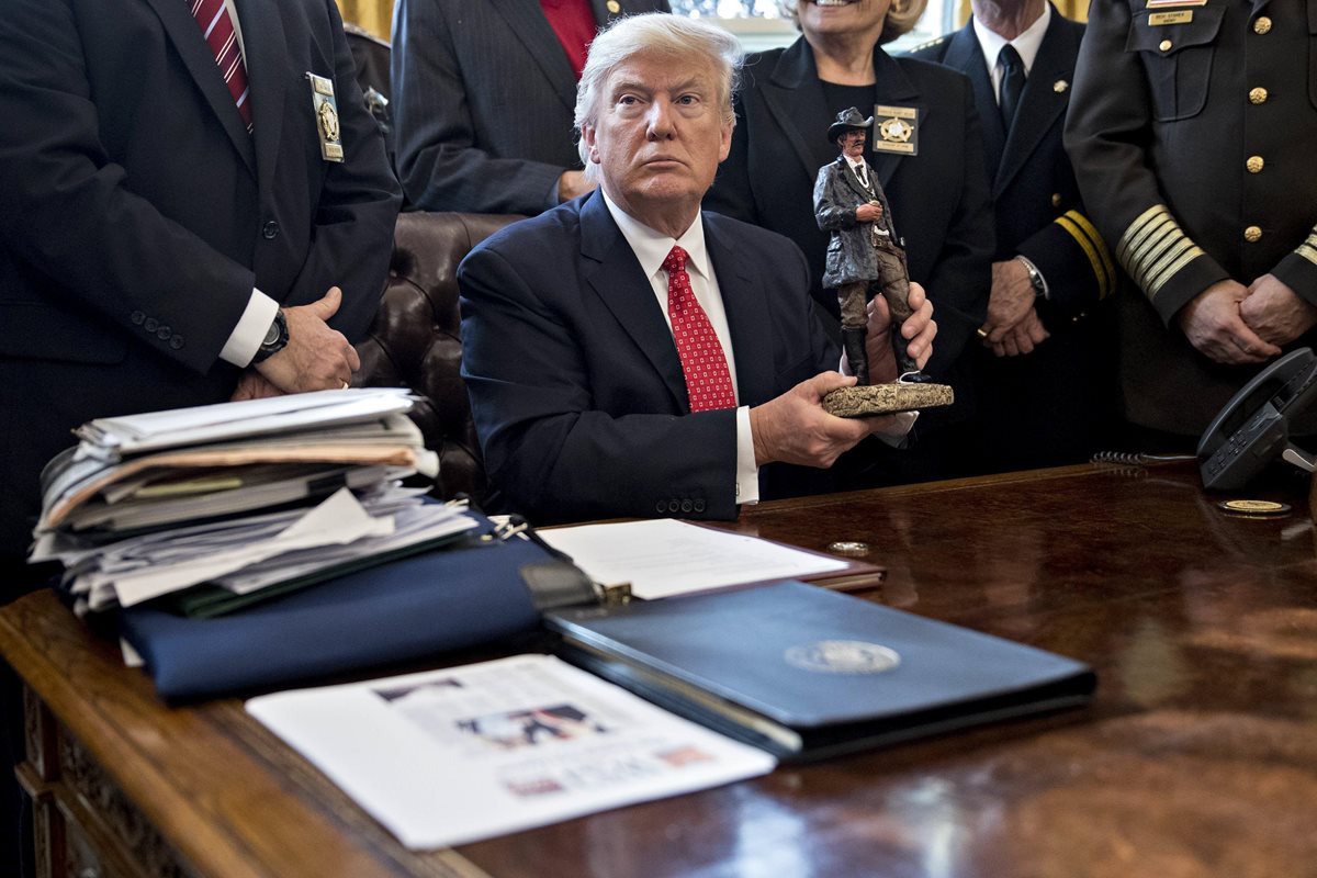 Trump sostiene una figura que le obsequiaron durante una reunión en el Despacho Oval. (Foto Prensa Libre:EFE).