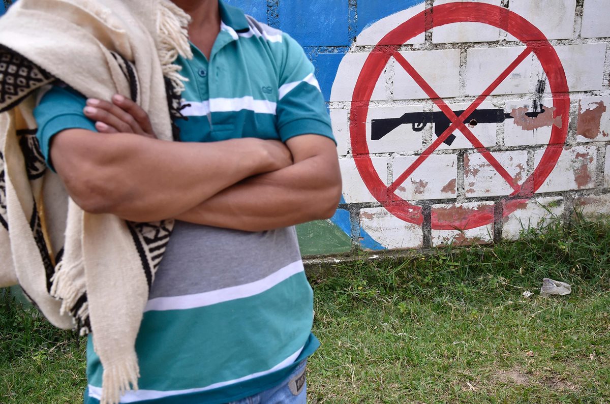 Un indígena posa en Tolima, Colombia, frente a un mural que evoca rechazo a la guerra en ese país. (Foto Prensa Libre: AFP).