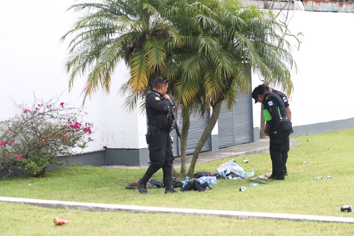 Agentes de la PNC resguardan los cadáveres de dos de las víctimas atacadas a balazos en la calzada Roosevelt. (Foto Prensa Libre: Érick Ávila)