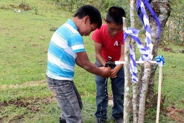 Niños disfrutan líquido que proviene de un reservorio que capta agua de lluvia. (Foto Prensa Libre: Óscar Figueroa)