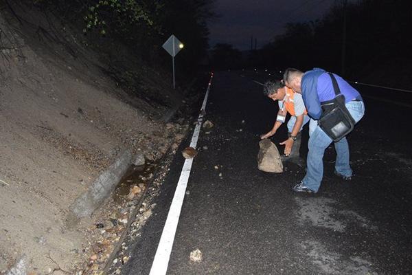 Lobsan Cordón de la Conred y un vecino quitan una piedra en el kilómetro 156 de la ruta entre Zacapa y Chiquimula. (Foto Prensa Libre: Víctor Gómez)