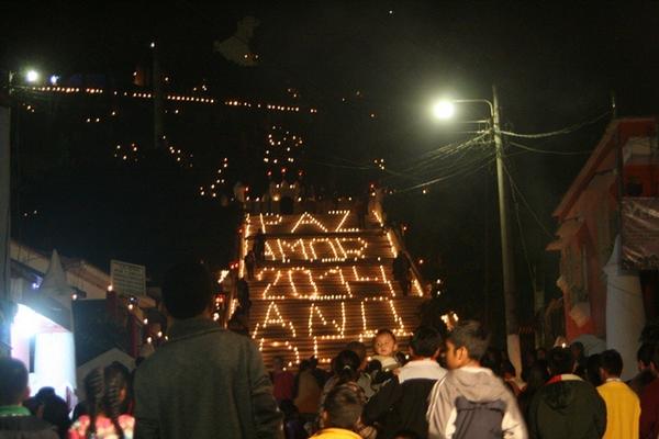 Vecinos y visitantes observan las palabras formadas con veladoras en la gradas del templo El Calvario, en Cobán. (Foto Prensa Libre: Ángel Tax)
