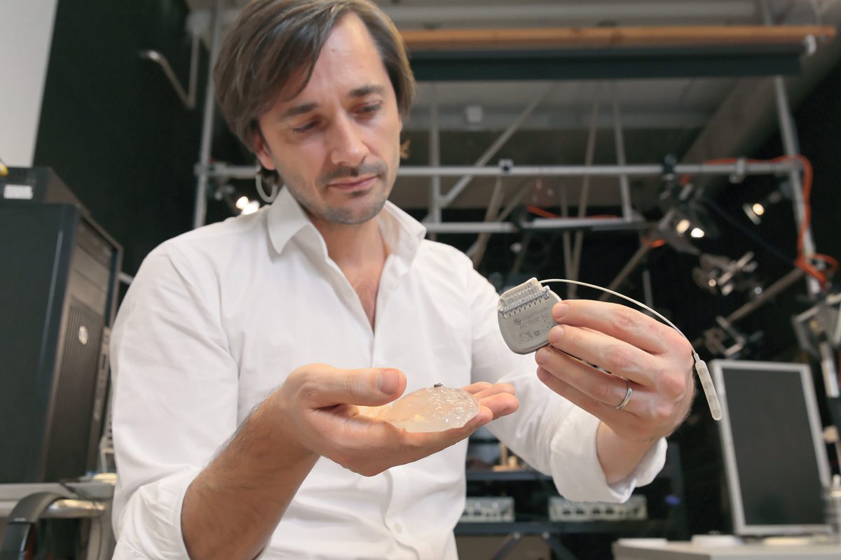 El científico Gregoire Courtine, del Centro de Neuroprótesis del Instituto Federal Suizo de Tecnología, sostiene un modelo de silicón de un cerebro de primate, un microelectrodo y un generador de pulso. (Foto Prensa Libre, AFP)
