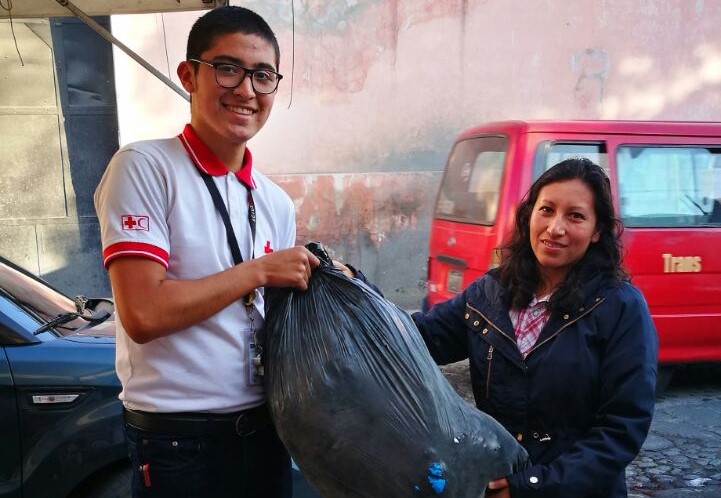 Cristian Rodas, voluntario, recibe uno de los donativos entregados por una vecina de Xela. (Foto Prensa Libre: María José Longo).
