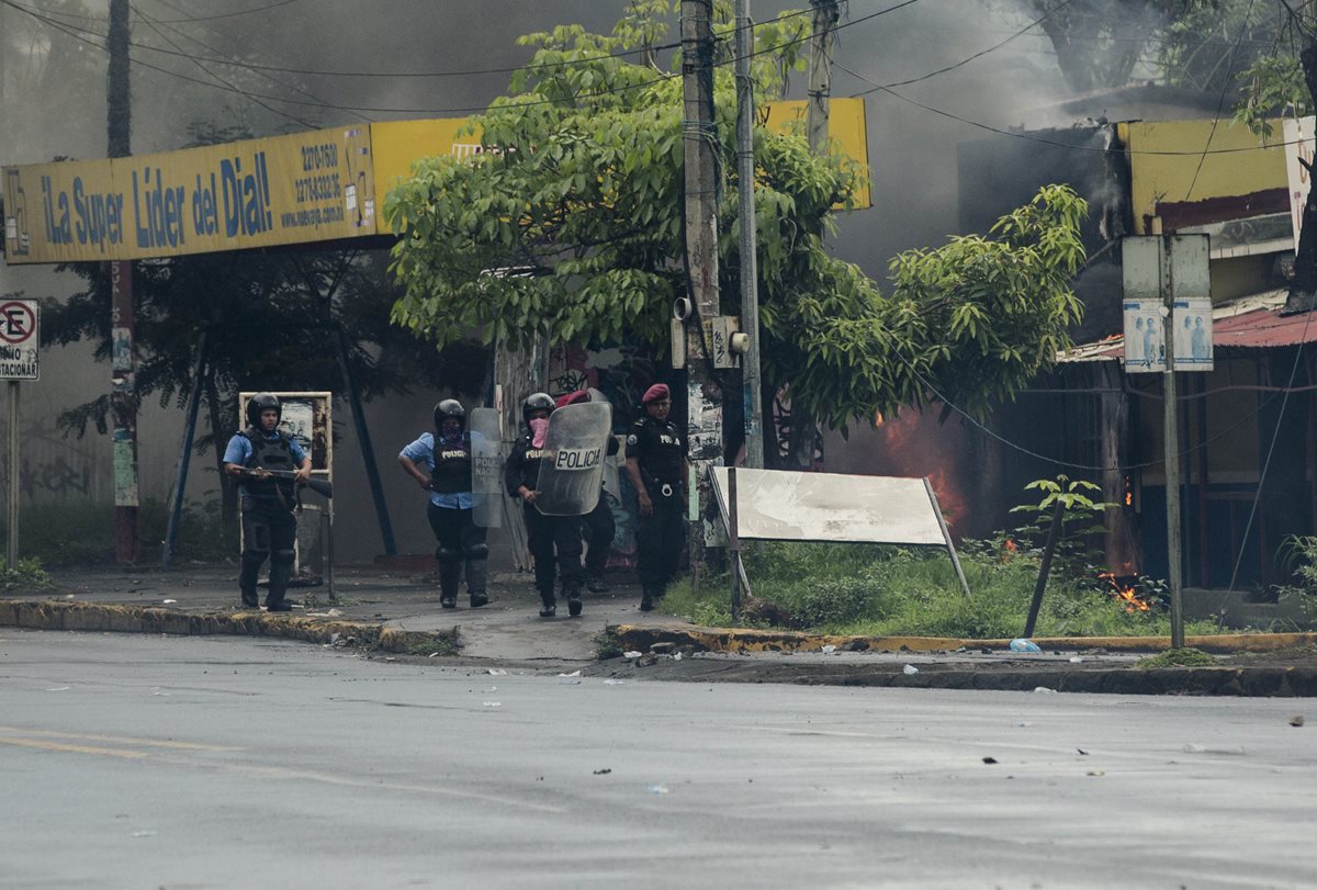 Policías intentan apagar las llamas en "La Nueva Radiio Ya", principal medio de comunicación del Gobierno. (Foto Prensa Libre: EFE)