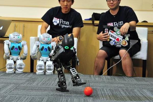 Estudiantes del laboratorio de robótica de la Universidad de Pensilvania observan a sus robots jugar al futbol. (Foto Prensa Libre: AFP)