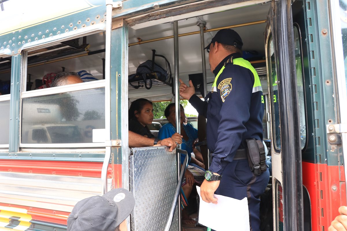 Un agente de la PMT de Escuintla pregunta a usuarios de un bus extraurbano si les han cobrado más de la tarifa acostumbrada. (Foto Prensa Libre: Enrique Paredes).