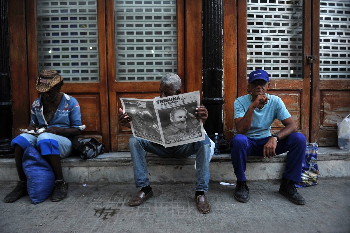 Un cubano lee el periódico en una calle de La Habana, tres dias después de la muerte del máximo líder, Fidel Castro. (Foto Prensa Libre: AFP).