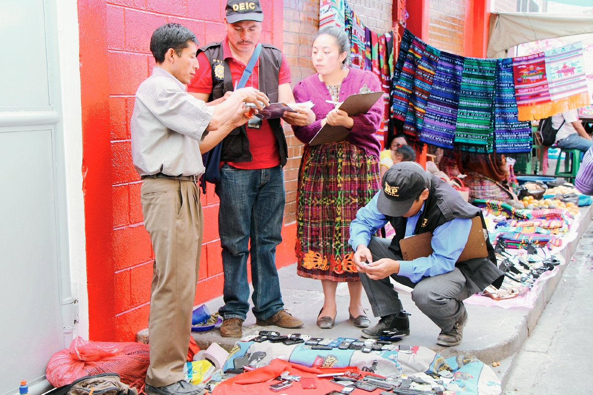 Investigadores de  la PNC y del MP verifican el registro de teléfonos móviles, en ventas informales y locales comerciales de Totonicapán. (Foto Prensa Libre: Édgar Domínguez)