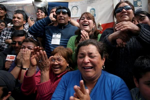 Conocidos de los mineros Víctor Zamora and Carlos Barrios reaccionan con aplausos y gritos al observar el rescate en la mina ubicada en Copiapó, Chile. (Foto Prensa Libre: AFP)