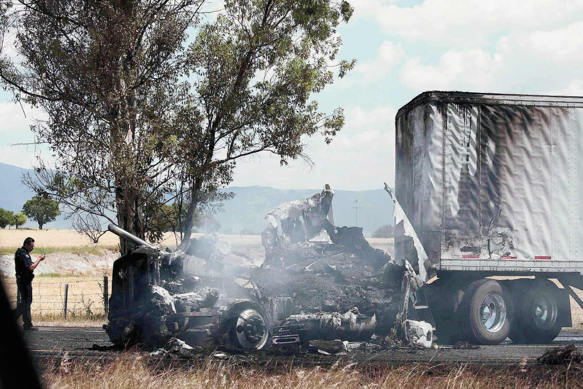 Investigadores observan un vehículo incendiado en Jalisco, México. (Foto Prensa Libre: AFP)