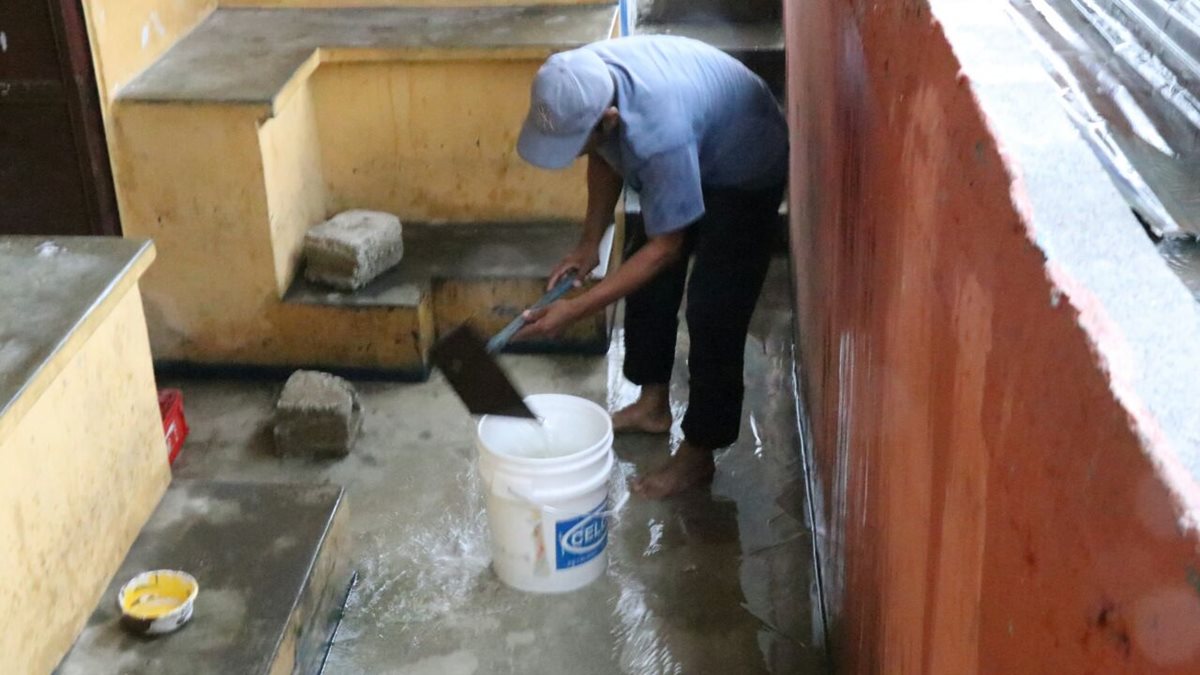 Un trabajador del estadio saca agua con una cubeta en la entrada del banquillo al camerino del estadio. (Foto Prensa Libre: Cristian Soto)