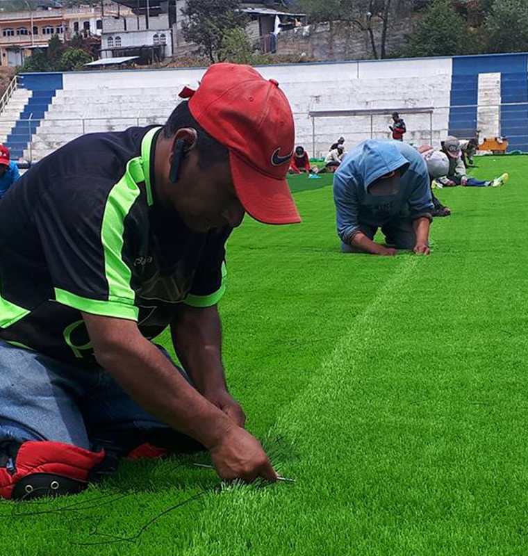 Empleados de la empresa contratada instala la gramilla sintética en el campo de futbol de Comitancillo. (Foto Prensa Libre: Whitmer Barrera)