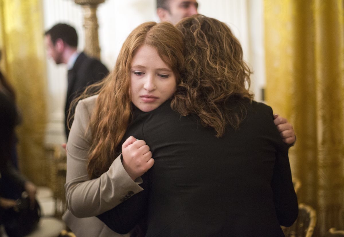 Familiares de víctimas de masacres en EE. UU. se abrazan durante el anuncio de Obama, el martes último. (Foto Prensa Libre: AP).