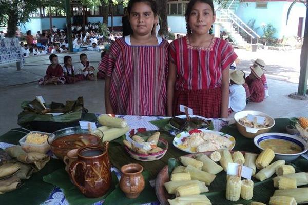 Dos estudiantes de la Escuela Oficial de la Aldea Los Cerritos, Chiquimulilla, muestran algunos de los platillos de la exposición de gastronomía Xinca. (Foto Prensa Libre: Oswaldo Cardona).