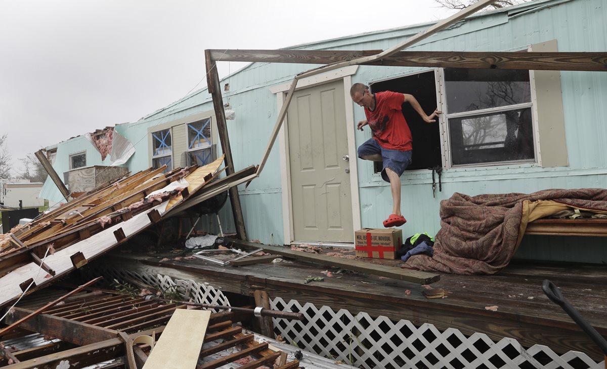 Sam Speights sale por la ventana de su cada después de ser destruida por el huracán Harvey.