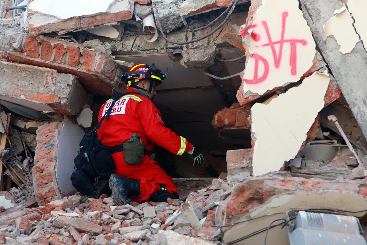 Un bombero peruano intenta escuchar una presunta persona atrapada en los escombros en la localidad de Manta. (Foto Prensa Libre: EFE).