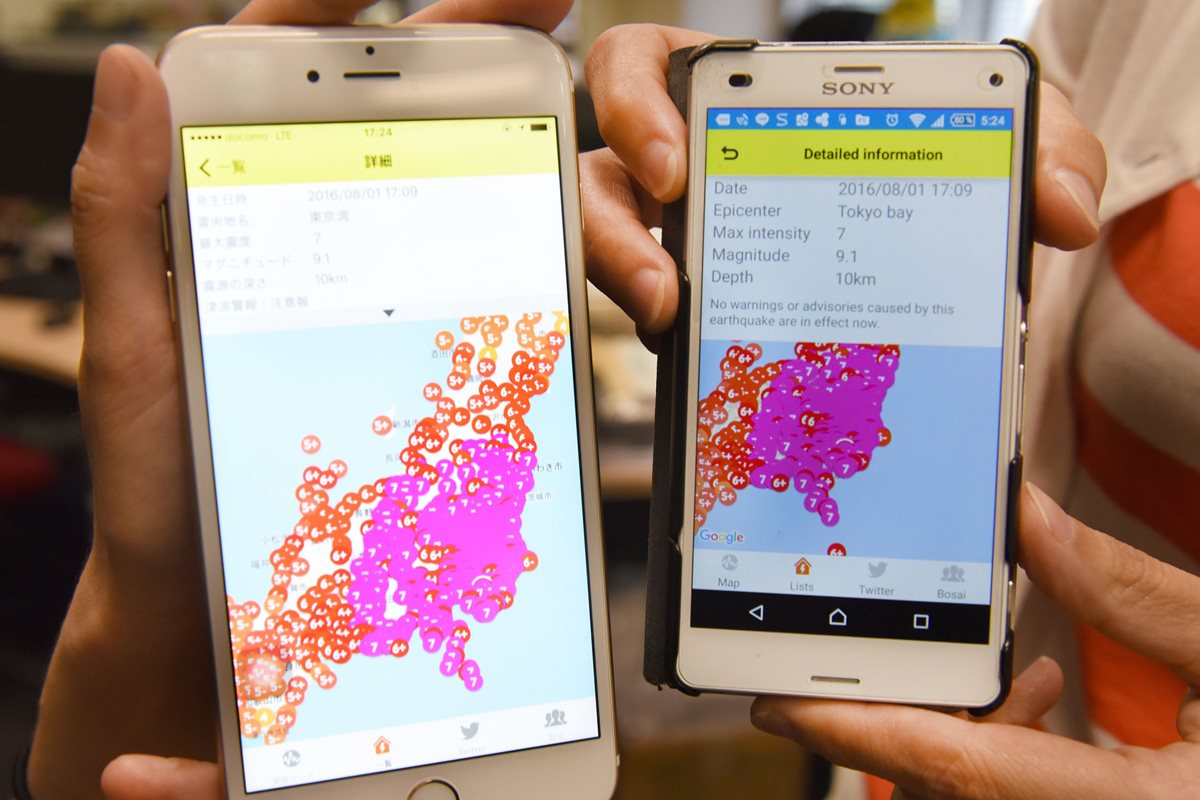 Japoneses muestras sus teléfonos con la advertencia de un potente sismo en Tokio que resultó ser falsa alarma. (Foto Prensa Libre: AFP).
