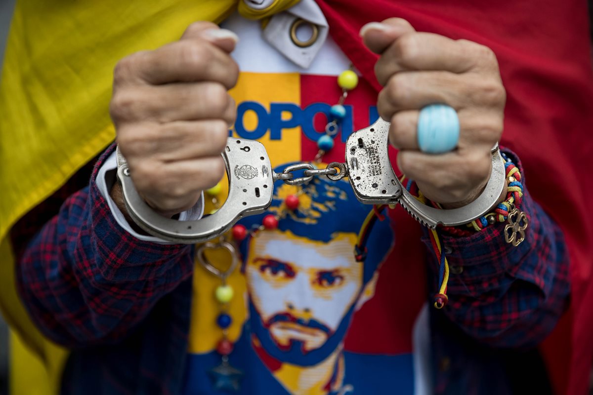 Una manifestante usa unas esposas con una franela del líder opositor venezolano Leopoldo Lopez durante una manifestación "Héroes por la Libertad". (Foto Prensa Libre:EFE).