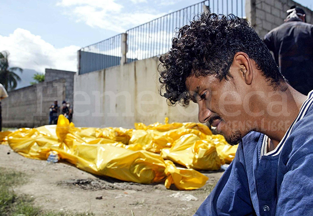 Un reo permanece junto a los cadáveres de sus compañeros fallecidos en un incendio en San Pedro Sula en 2004. (Foto: AFP)