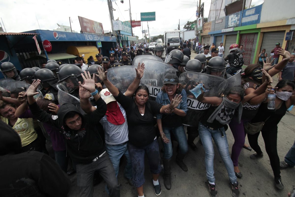 Pobladores se enfrenta a agentes de la PNC en un intento de evitar que retiren el bloqueo de ingreso a San Pedro Ayampuc.(Foto Prensa Libre: Erick Ávila)