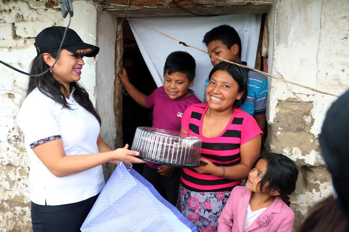 Andrea Cabrera de Ánfora entrega el pastel de chocolate a Iris Coyoy y su familia. (Foto Prensa Libre: Carlos Ventura)